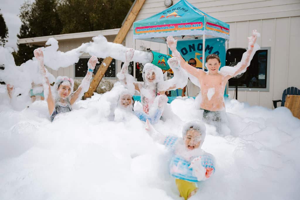 Kids cheering with arms up in a white foam party rental in Sonoma