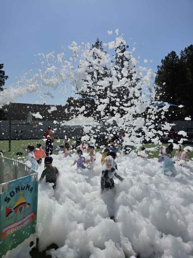 Large group of kids playing in a daytime foam party rental